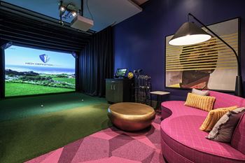 A game room with a pink couch and a view of the golf course