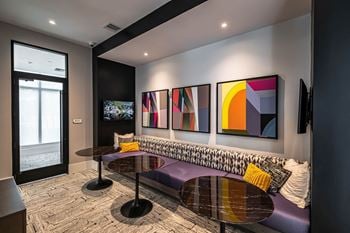 A living room with paintings on the wall and a purple couch