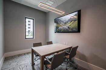 A conference room with a tv and a table with chairs