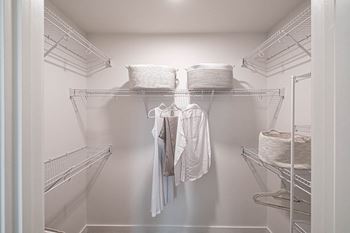 A walk in closet with wire shelves and clothes