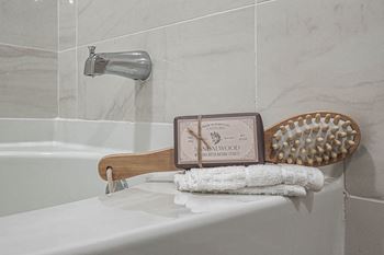A white bathroom with a towel rack and a soap dispenser and a bath tub