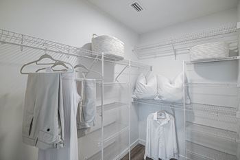 A large walk in closet with white clothing and pillows