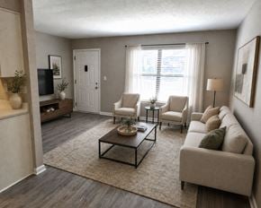 Louisville apartment for rent - A living room with a white sofa, a coffee table, and a television.