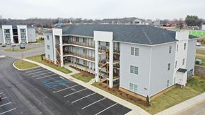 Louisville apartment for rent - A parking lot with a blue painted sign in front of a white building.