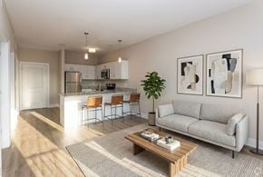 Clarksville apartment for rent - A living room with a grey couch, a coffee table, and a kitchen in the background.