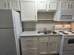 Louisville apartment for rent - a kitchen with white cabinets and stainless steel appliances and a refrigerator