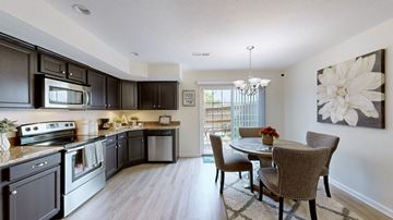 Louisville townhouse for rent - A kitchen with dark brown cabinets and a dining table with chairs.