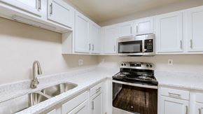 Louisville apartment for rent - A kitchen with white cabinets and a stove and microwave..