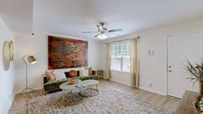 Louisville townhouse for rent - A living room with a green couch, a coffee table, a painting, and a ceiling fan.