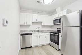 Florissant apartment for rent - A kitchen with white cabinets and a black fridge.