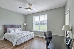 Evansville apartment for rent - a bedroom with a bed and a desk and a ceiling fan