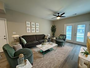 Louisville apartment for rent - A living room with a black sofa, green armchair, and a glass coffee table.