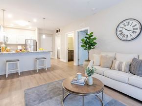 Clarksville apartment for rent - A living room with a white couch, a grey rug, and a clock on the wall.