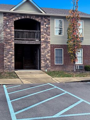 Richmond apartment for rent - A tree with red leaves is in front of a grey house.
