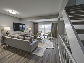 Columbus apartment for rent - A living room with a grey couch, a white rug, and a staircase.