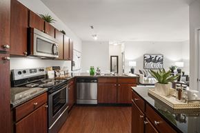 St. Peters apartment for rent - A kitchen with dark wood cabinets and a black counter top. at Aventura at Richmond, St. Peters, 63376