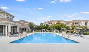 Lafayette apartment for rent - A large swimming pool surrounded by lounge chairs and umbrellas in a residential area, Plantation Crossing, Lafayette, LA, 70508