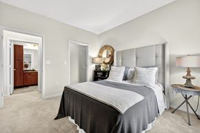 St. Charles apartment for rent - A bedroom with a large bed and a dresser with a mirror.