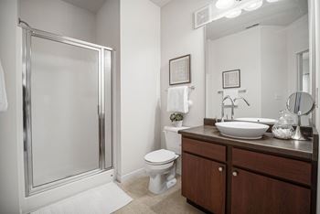 A bathroom with a toilet, sink, mirror, and shower.