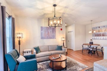 St. Louis apartment for rent - A living room with a grey couch, a blue chair, a wooden coffee table and a chandelier.