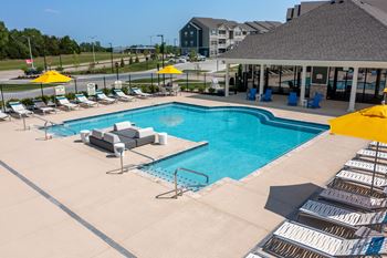 A swimming pool with lounge chairs and umbrellas in front of a building