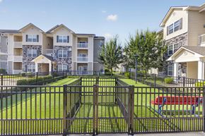 St. Louis apartment for rent - A black metal fence surrounds a green lawn in front of apartment buildings.
