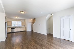 St. Louis townhouse for rent - an empty living room and kitchen with wood flooring and white walls