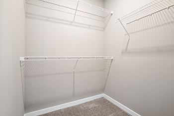 The spacious walk in closet in a bedroom of a home with white walls and shelves