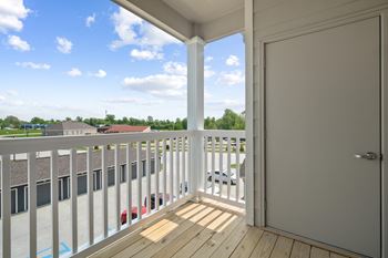 A balcony with a door and a view of a parking lot