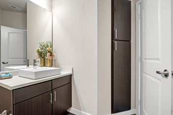 A bathroom with dark cabinets and a white sink