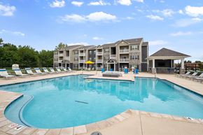 Wentzville apartment for rent - A large swimming pool in front of a multi-story apartment building at Aventura at Wentzville I & II Apartments, Wentzville, Missouri