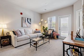 A living room with a white couch, a coffee table, and a painting on the wall.