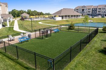 A black fence surrounds a green lawn with a pool and a playground.