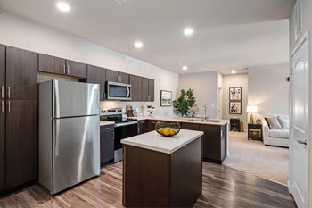 A modern kitchen with a refrigerator, microwave, and oven.