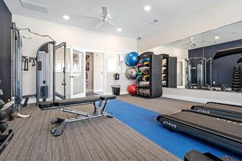 A well equipped gym with a mirrored wall and a variety of exercise equipment.