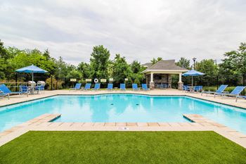 A pool with blue loungers and a gazebo.