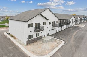 De Pere townhouse for rent - A white building with a grey roof is surrounded by other similar buildings.