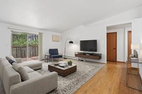 Wausau apartment for rent - A living room with a grey sofa, a blue chair, a wooden coffee table, and a flat screen TV.