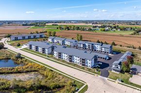 Kaukauna apartment for rent - A large building complex with a parking lot in front.