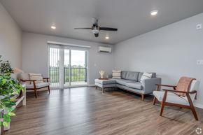 Kaukauna apartment for rent - A living room with a grey sofa, wooden chairs, and a ceiling fan.