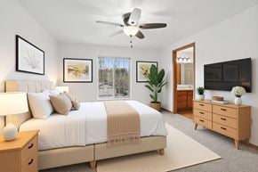 Wausau apartment for rent - A bedroom with a large bed, a ceiling fan, and a window with a view of trees.