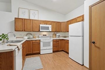 Wausau apartment for rent - A kitchen with wooden cabinets and white appliances.