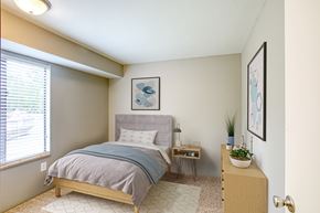 Kalamazoo apartment for rent - A bedroom with a bed, nightstand, and a plant on a dresser.