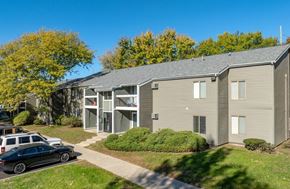 Kalamazoo apartment for rent - A black car is parked on a driveway in front of a two-story apartment building.