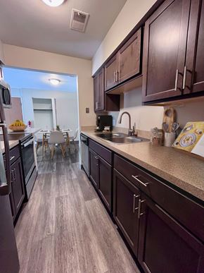 Kalamazoo apartment for rent - A kitchen with dark wood cabinets and a light brown floor.