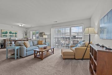 Rockford apartment for rent - A living room with a blue couch, a yellow couch, a wooden coffee table, and a painting on the wall.
