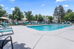 Kalamazoo apartment for rent - A large swimming pool surrounded by lounge chairs and umbrellas.