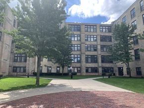 Muskegon apartment for rent - A large building with a brick walkway in front.