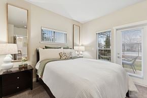Richland apartment for rent - A bedroom with a large bed, a dresser with a mirror, and a window with blinds.