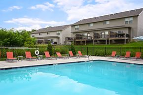 Riverside townhouse for rent - A swimming pool in front of a building with red chairs around it.